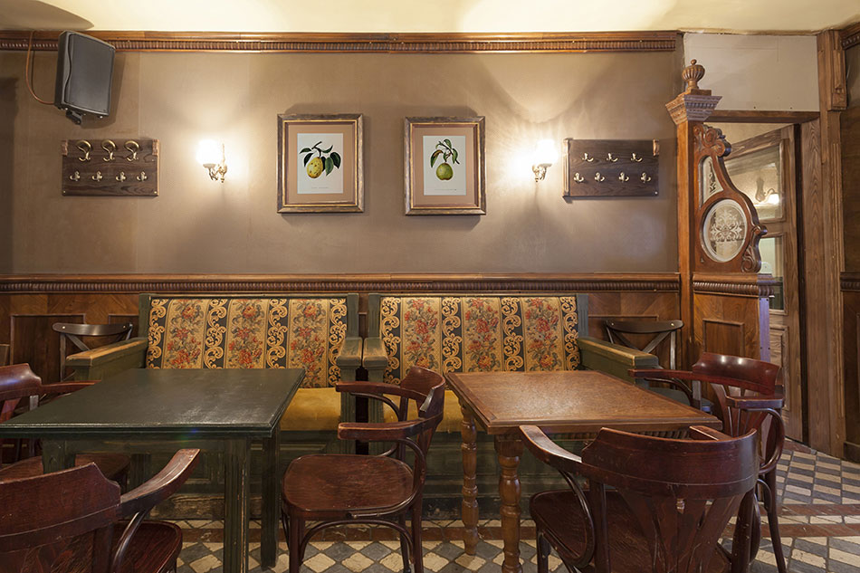 Гравюры с грушами в рамах с паспарту над столиком в баре в стиле кантри